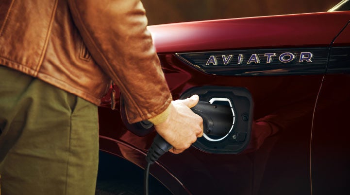 A hand is shown plugging in the charger into the charging port of a 2021 Lincoln Aviator | Pines Lincoln in Pembroke Pines FL