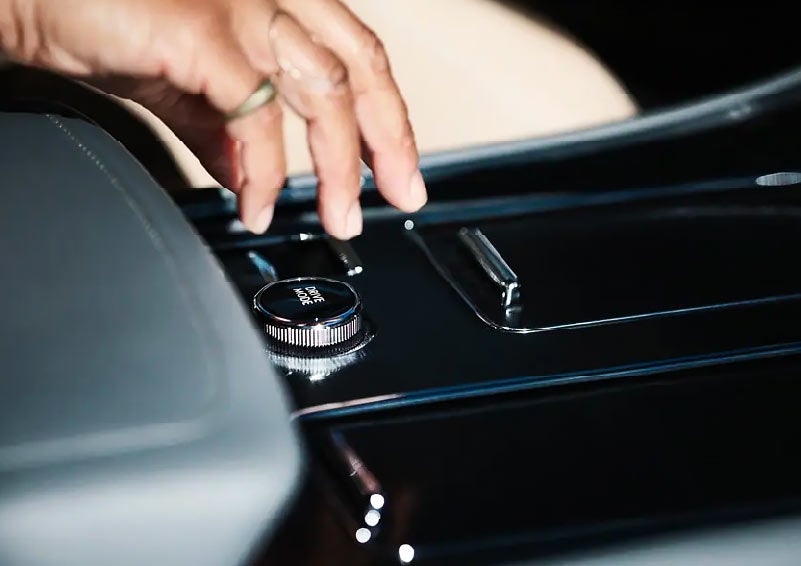 A driver reaches for the drive modes selector knob in the center console